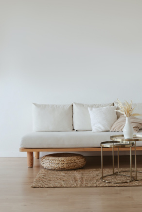 Vaalea puurunkoinen sohva, juuttikankainen matto, rottinkinen rahi ja metallinen sohvapöytä