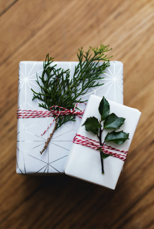 Kauniilla oksilla koristellut joululahjapaketit vaaleassa lahjapaperissa